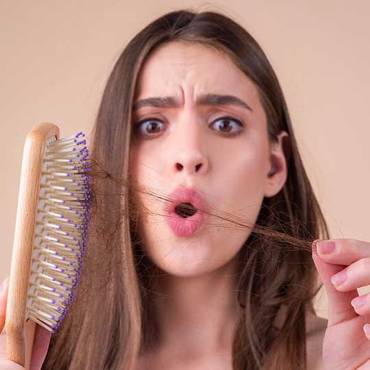 Mujer con un mechón de pelo en el peine sorprendida por saber cual es el mejor tratamiento capilar más efectivo.